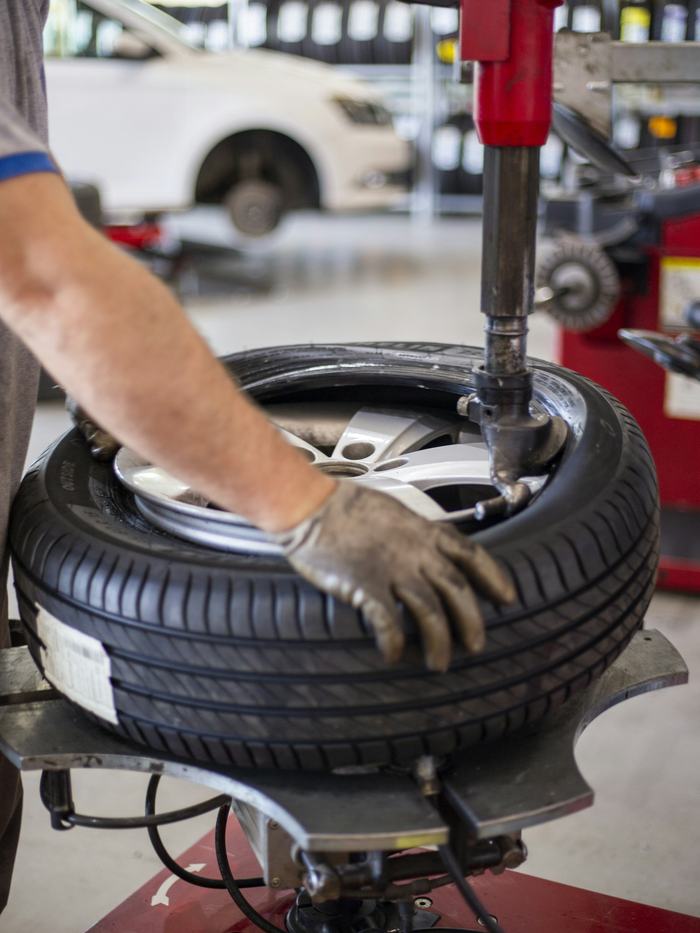 Sample photo: a gloved hand guiding a tire on a tire-changer machine